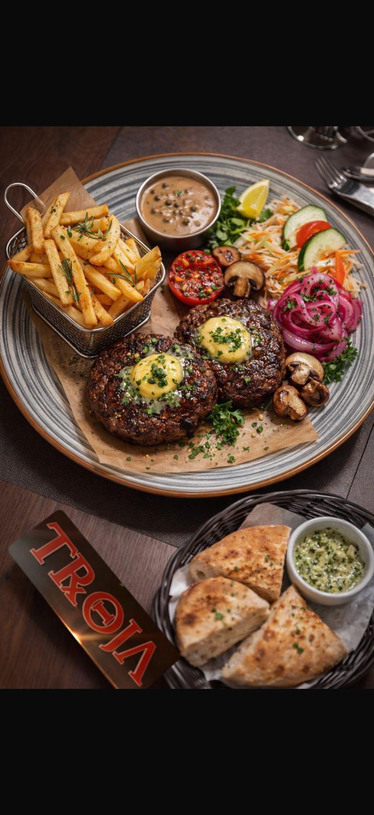 Hausplatte mit Steak, Pommes, Mushroom-Sauce und Beilagen auf rustikatem Holzbrett